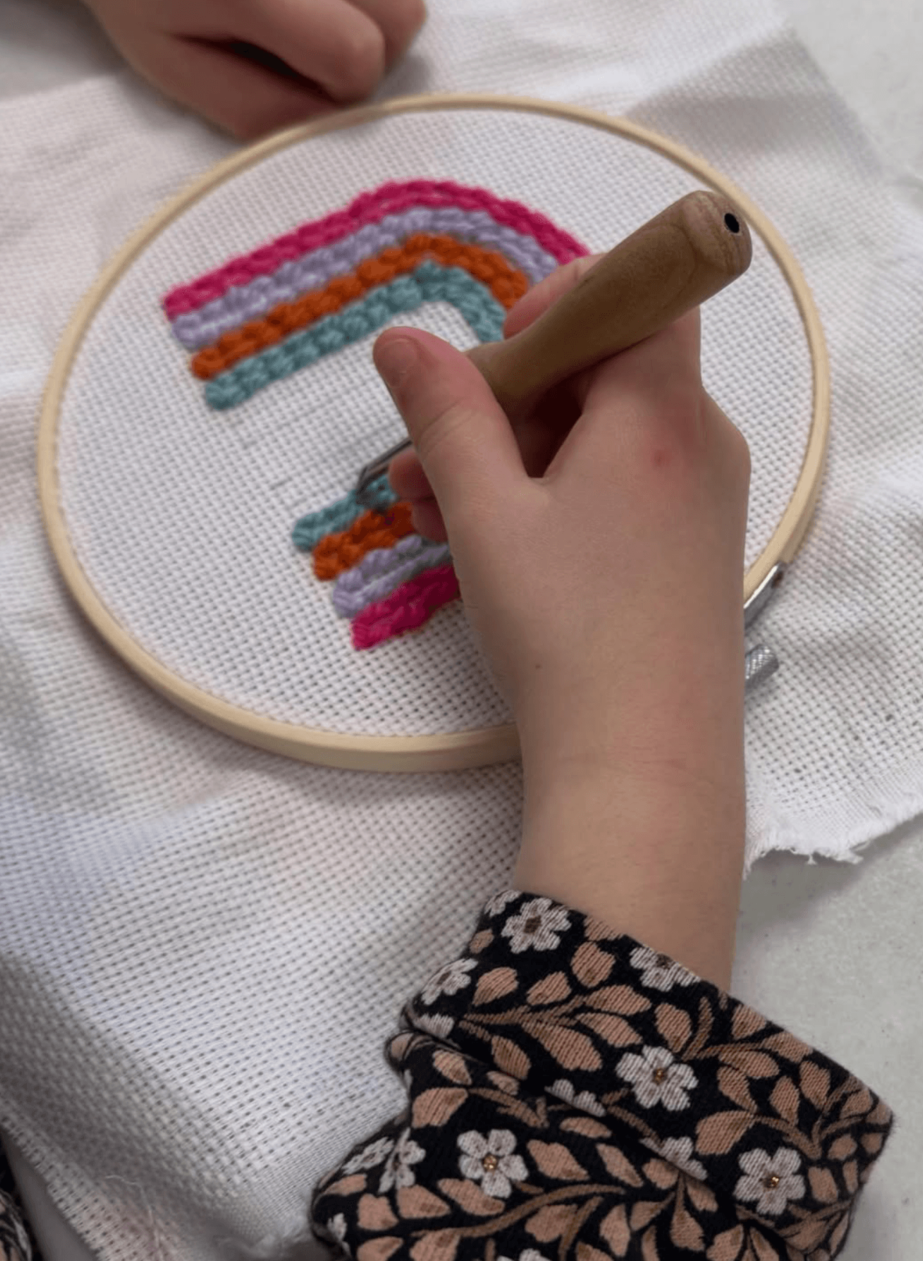 Enfant réalisant un arc-en-ciel en punch needle lors d'un atelier créatif à Jaunay-Marigny